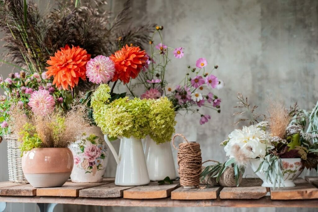 An array of fresh cut flowers in vases on an old wooden table