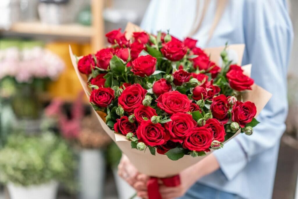 A person holds a bouquet of red roses
