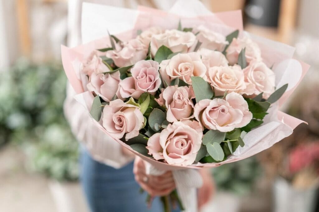 A person holds aloft a bouquet of pink roses