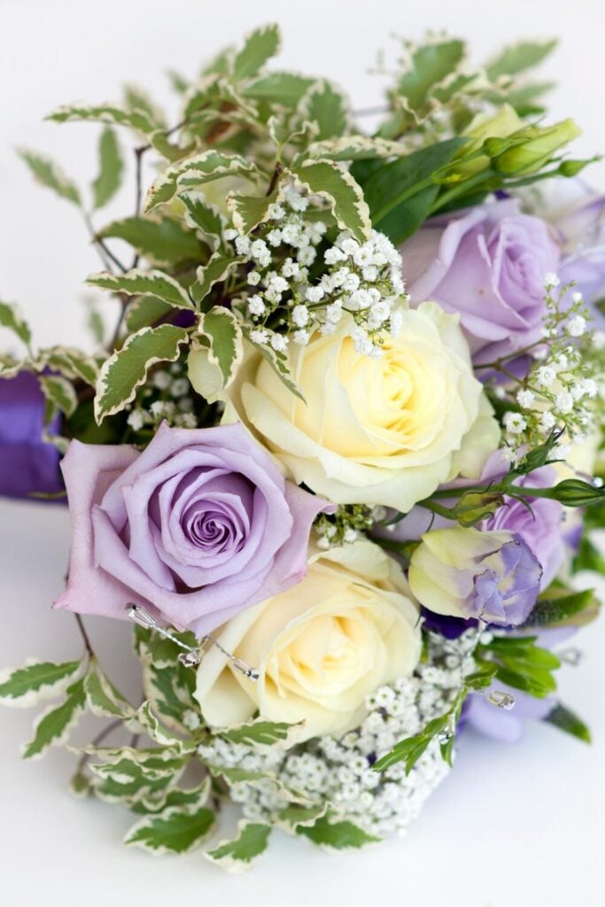 Bouquet featuring lavender and cream roses with variegated leaves and baby's breath