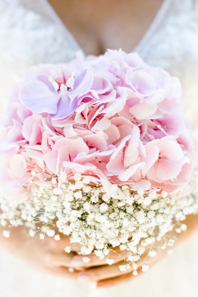 Bridal bouquet with pink hydrangeas, lavender orchid accents, and a halo of Baby’s Breath, exuding softness and charm.