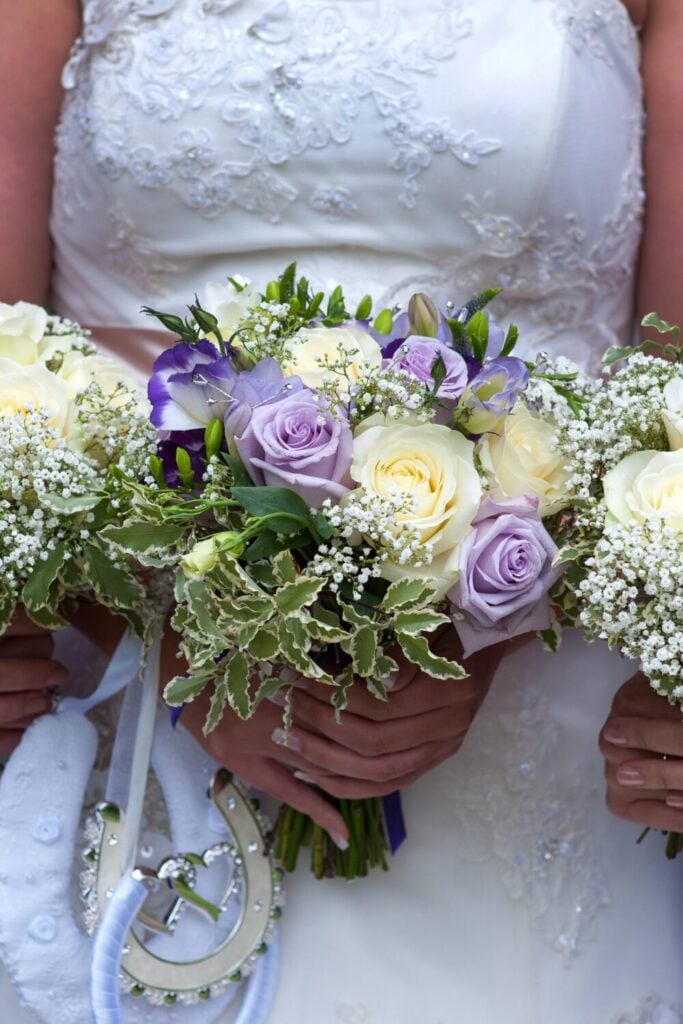 Bridal bouquet with lavender and ivory roses, Baby’s Breath, and variegated greenery, exuding soft elegance and charm.