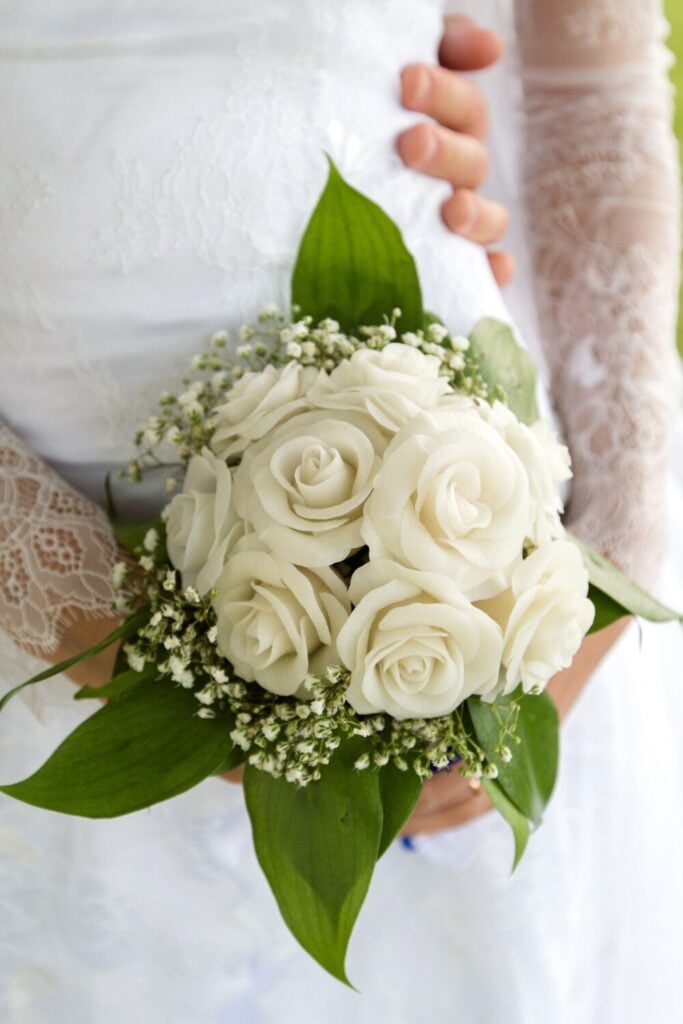 Bridal bouquet with white roses, Baby’s Breath, and green foliage for a classic and elegant wedding look.