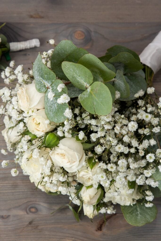 Wedding bouquet with eucalyptus leaves, ivory roses, and Baby’s Breath, styled for a rustic yet elegant vibe.