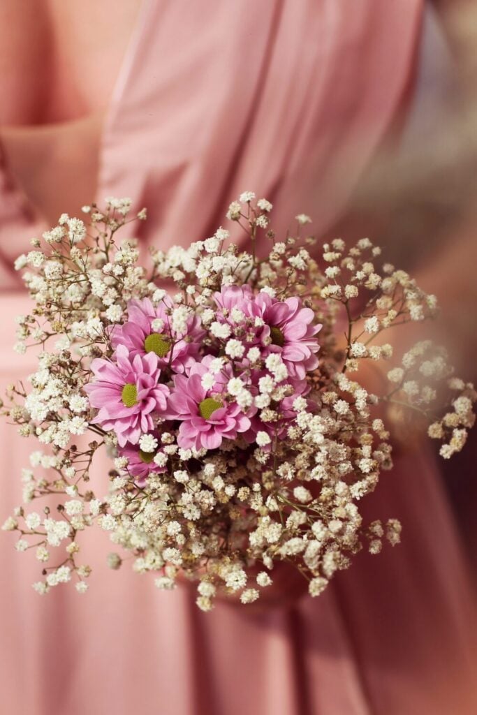 Bouquet of bright pink daisies surrounded by a cloud of Baby’s Breath, perfect for a whimsical wedding look.