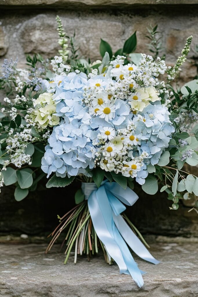 Blue hydrangea and daisy wedding bouquet with Baby’s Breath and eucalyptus, tied with a blue ribbon.