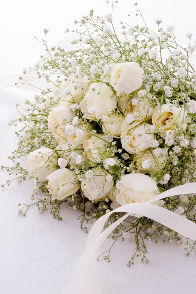 Wedding bouquet with cream roses and baby's breath tied with white ribbon