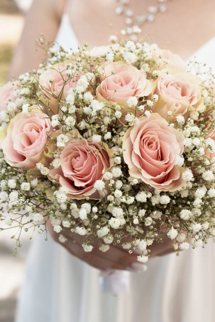 Round bridal bouquet featuring pink roses surrounded by delicate baby's breath