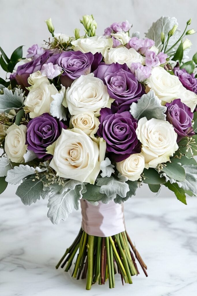 Modern bridal bouquet with lavender and cream roses, dusty miller, and lilac blooms tied with a blush ribbon.