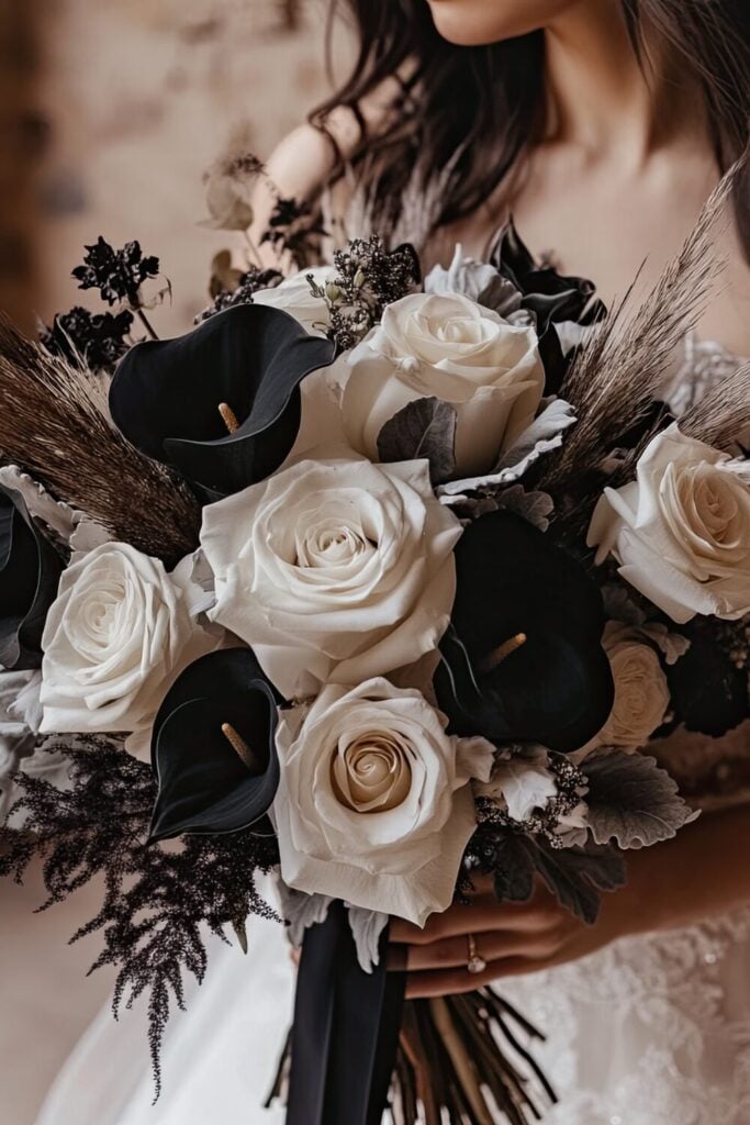 A bold bridal bouquet pairs classic white roses with striking black calla lilies and feathery dried accents