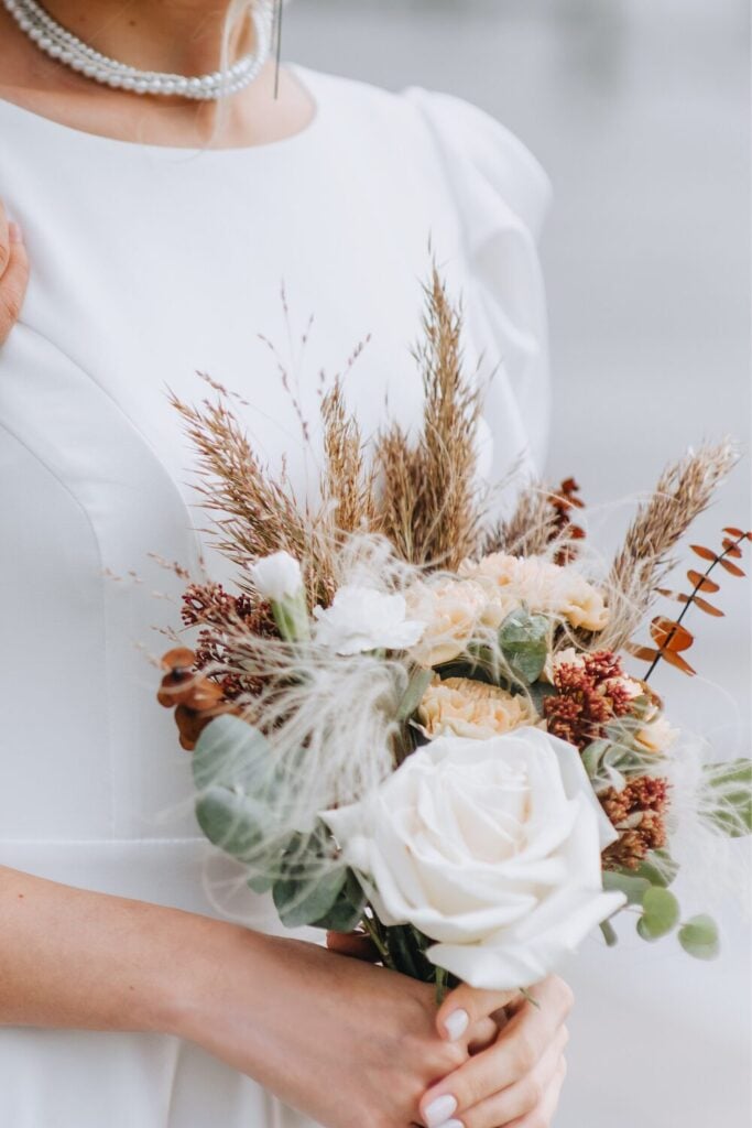 Autumnal White Rose Wedding Bouquet held by a bride