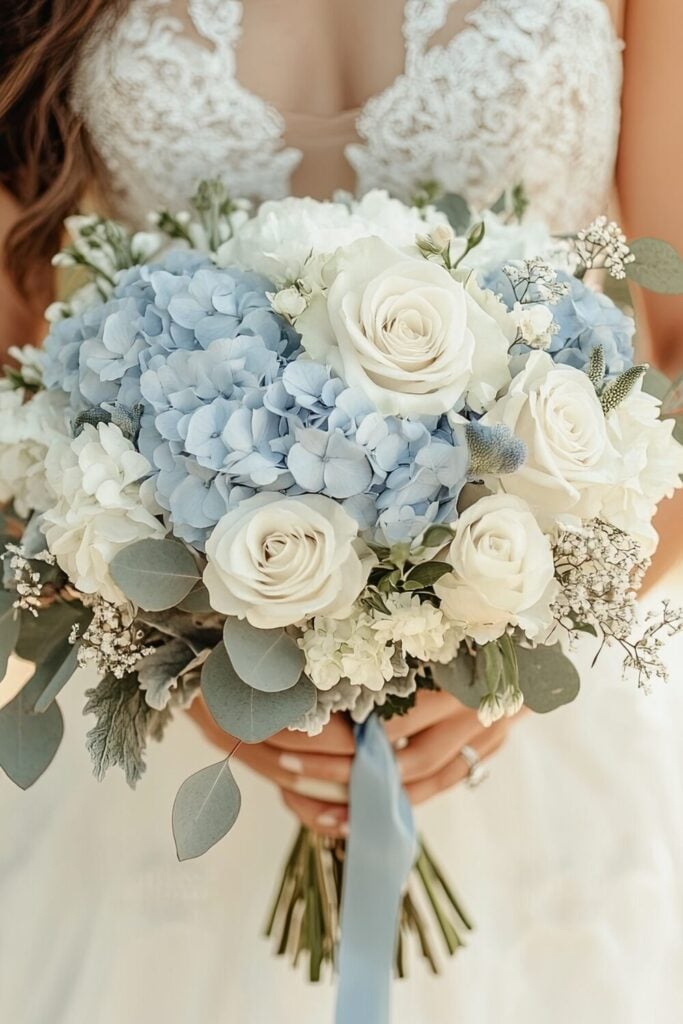 Blue hydrange and white rose wedding bouquet tied with a ribbon and held by a bride.