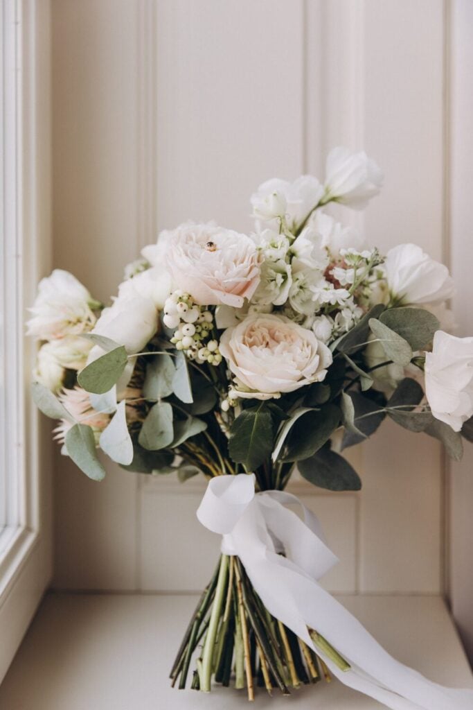 Wedding bouquet featuring blush peonies, snowberries, and flowing eucalyptus.