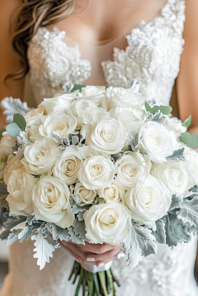 White Rose wedding bouquet with Dusty Miller leaves held by a bride.